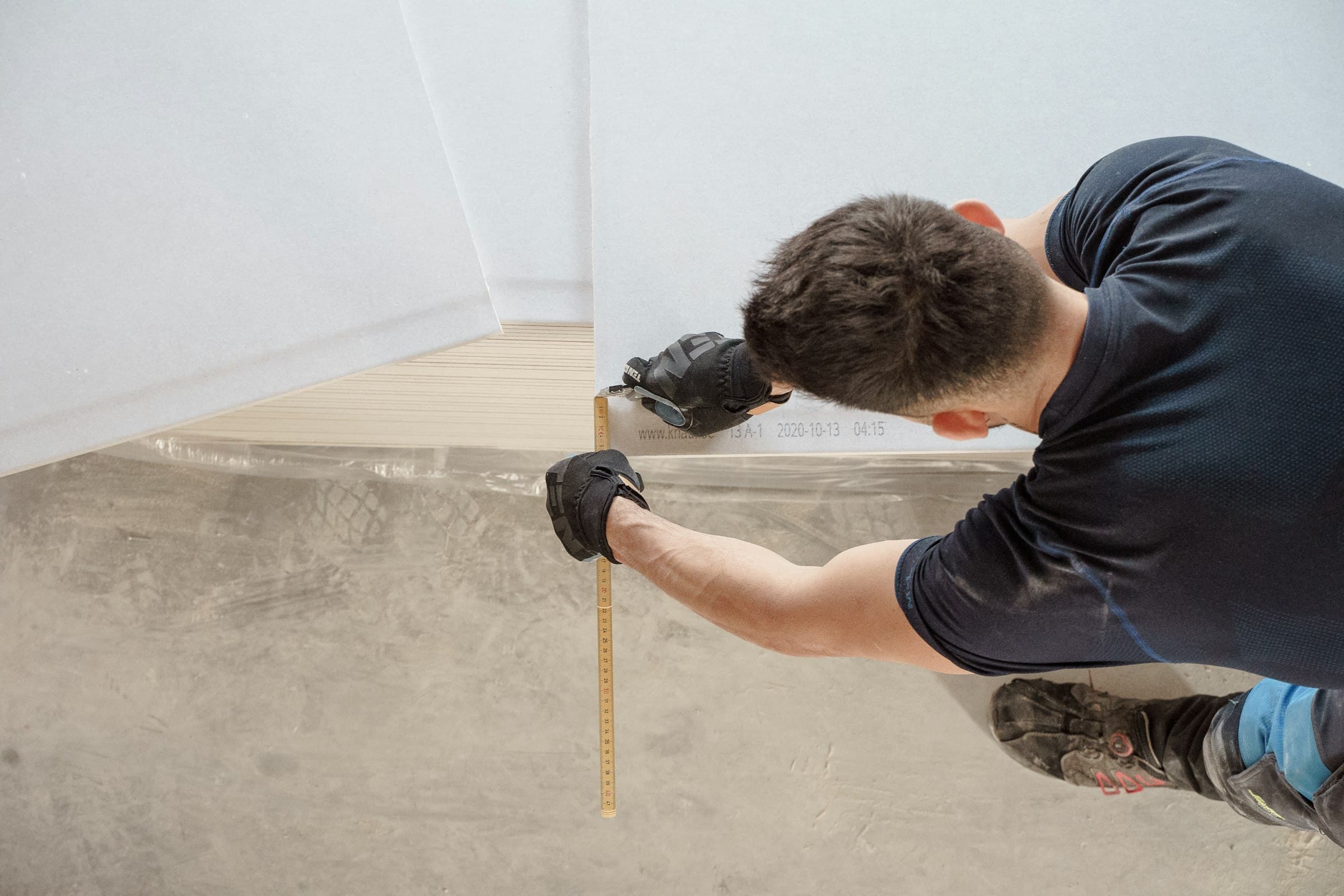 Person measuring a wood board with a tape measure